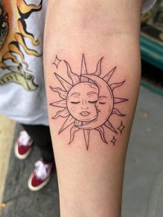 a woman's arm with a sun and moon tattoo on the left side of her leg