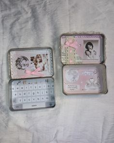 three tins that have pictures in them on top of a bed with white sheets