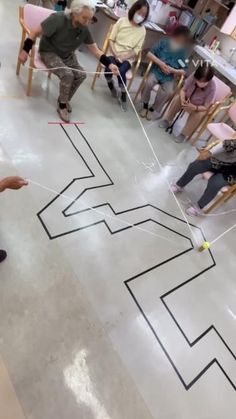 a group of people sitting in chairs around a drawing on the floor