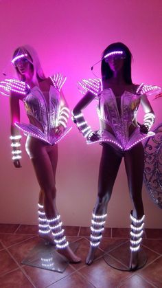 two mannequins with lights on their arms and legs in front of a pink background