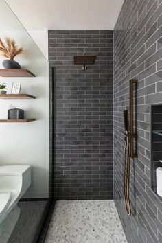 a walk in shower sitting next to a white toilet and wall mounted faucet