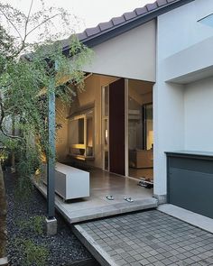 an outdoor living room and patio area in a modern style home with white walls, grey tile flooring and brick pavers