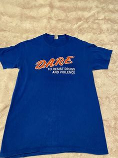 D.A.R.E. Dare Officially Licensed Keeping Kids Off Drugs Blue T-Shirt S Blue Band Merch T-shirt With Logo Print, Blue Band Merch T-shirt With Graphic Print, Blue Band Merch T-shirt With Logo, Retro Blue T-shirt With Text Print, Retro Blue Tops With Letter Print, Retro Blue Top With Letter Print, Vintage Blue Tops With Letter Print, Blue Band Merch Tops With Logo Print, Blue Band Merch Top For Streetwear