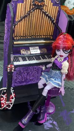 a doll sitting next to a purple piano