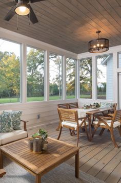 a porch with wooden furniture and large windows