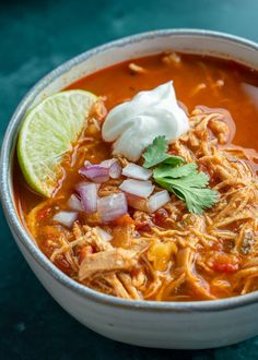 a bowl of chicken tortilla soup with sour cream and cilantro garnish