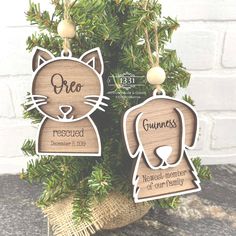 two wooden ornament shaped like cats sitting on top of a tree