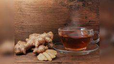 a cup of tea next to sliced ginger on a wooden table