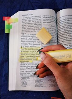 a person holding a pen and writing on an open book with sticky notes attached to it