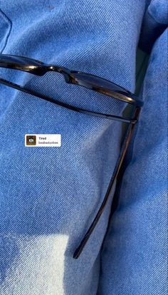 a pair of black glasses sitting on top of a blue pillow with a sticker