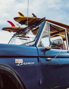 an old blue truck with surfboards on top