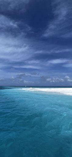 the ocean is blue and clear with some clouds