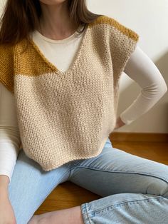 a woman sitting on the floor wearing a knitted sweater