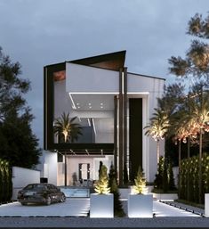 a car is parked in front of a modern house at night with palm trees and bushes