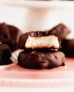 three chocolate covered donuts stacked on top of each other with one bite taken out