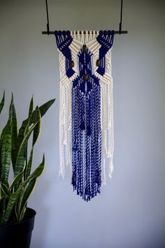 a blue and white wall hanging next to a potted plant