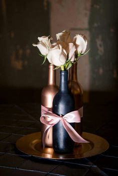 two vases with white flowers in them on a gold plated tableclothed surface