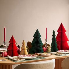 the table is set for christmas dinner with red and green trees on top of it