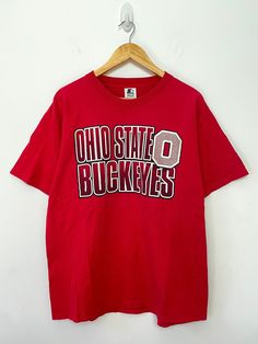 This tee shirt shows fading on the upper and lower front side. It also has some piling and slight cracking on the graphic. Measurements  Pit to pit (width): 22 inches Top to bottom (length): 27 1/2 inches Vintage College T-shirt With Lettering, 90s Crew Neck T-shirt For Fan Gear, 90s Style T-shirt For Fan Gear With Crew Neck, 90s Style Crew Neck T-shirt For Fan Gear, Vintage T-shirt With Lettering For College, Vintage Lettering T-shirt For College, 90s Style Red T-shirt For College, Vintage Red T-shirt For College, College Tees