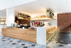 an open bar with lots of bottles on the wall and shelves behind it in a large room