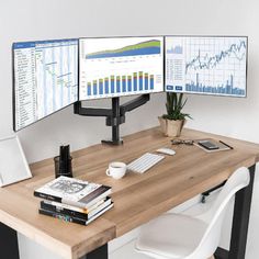 two computer monitors sitting on top of a wooden desk