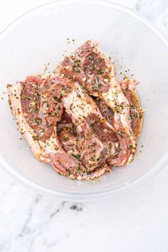 raw meat in a glass bowl with seasoning on top