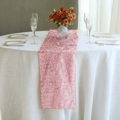 the table is set with silverware, wine glasses and a pink napkin on it