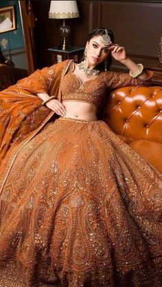 a woman sitting on top of a couch wearing a brown dress and headpieces