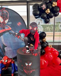 a spiderman birthday party with balloons and decorations in the shape of people on top of a cake