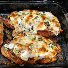 three chicken parmesan patties in a pan with cheese and spinach on top