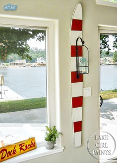 a red and white surfboard mounted to the side of a wall next to a window