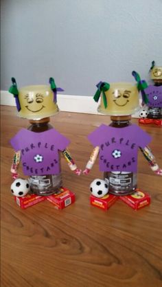 three plastic cups with faces on them sitting on top of a wooden table next to soccer balls