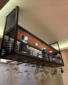 several wine glasses are hanging from the ceiling in front of a rack with lights on it