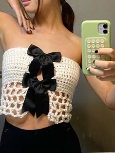 a woman taking a selfie with her cell phone wearing a crocheted crop top