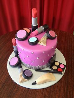 a pink cake with makeup and lipstick on it