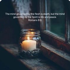 a candle sitting on top of a window sill next to a glass jar filled with rocks