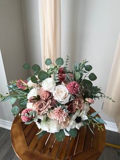 a bouquet of flowers sitting on top of a wooden table in front of a window