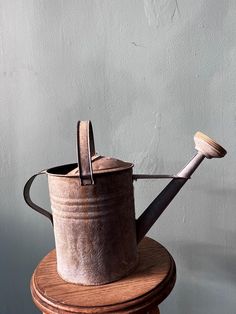 an old watering can sitting on top of a wooden stand with a shovel in it