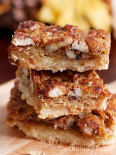 three pieces of food sitting on top of a wooden cutting board next to some nuts