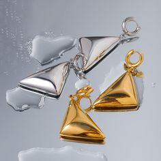 Meet your new statement piece: the Vanguard Gold Earrings. These sleek, geometric beauties are designed to turn heads and elevate your style game. Crafted with a high-shine 18 karat gold finish, these earrings feature a bold triangular design that dangles elegantly, creating a modern and sophisticated look. The unique pyramid shape of the earrings adds an edgy flair, making them perfect for both casual and formal outfits. Notice how they catch the light beautifully, highlighting the clean lines and smooth surfaces. The earrings are lightweight, ensuring comfortable wear all day long. Get ready to make a statement with the Vanguard Gold Earrings – the ultimate blend of contemporary design and timeless elegance. Elegant Triangle Metal Earrings, Modern Triangle Earrings For Party, Modern Triangle Gold Hoop Earrings, Modern Triangle Party Earrings, Modern Single Triangle Earring, Modern Triangle Metal Earrings, Black Friday Jewelry, Jewelry Organizer Storage, Natural Stone Bracelets