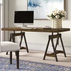 a desk with a computer on it and a chair next to it in front of a window