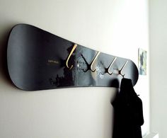 a snowboard mounted to the side of a wall next to a coat rack with hooks