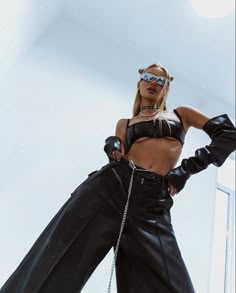 a woman in black leather pants and sunglasses posing for the camera with her hands on her hips