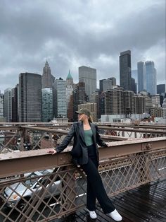 a woman standing on top of a bridge in front of the cityscape with skyscrapers