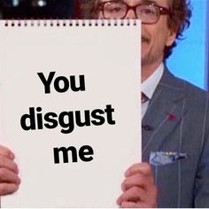 a man holding up a sign that says you disgust me