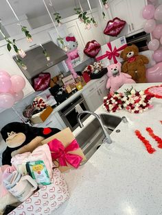 a kitchen decorated for valentine's day with pink balloons and teddy bears in the background