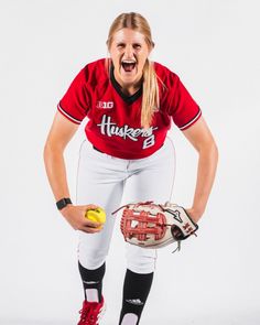 a female baseball player posing for a photo with her mitt and ball in hand