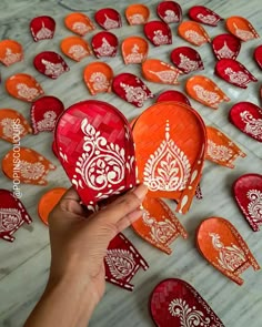 a person is holding up some red and white paper heart shaped boxes with designs on them