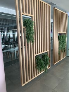 three wooden partitions with plants growing on them in an office building lobby, along with tables and chairs