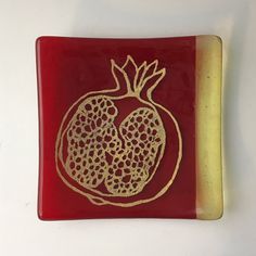 a red and gold plate with a pomegranate cut out on the side